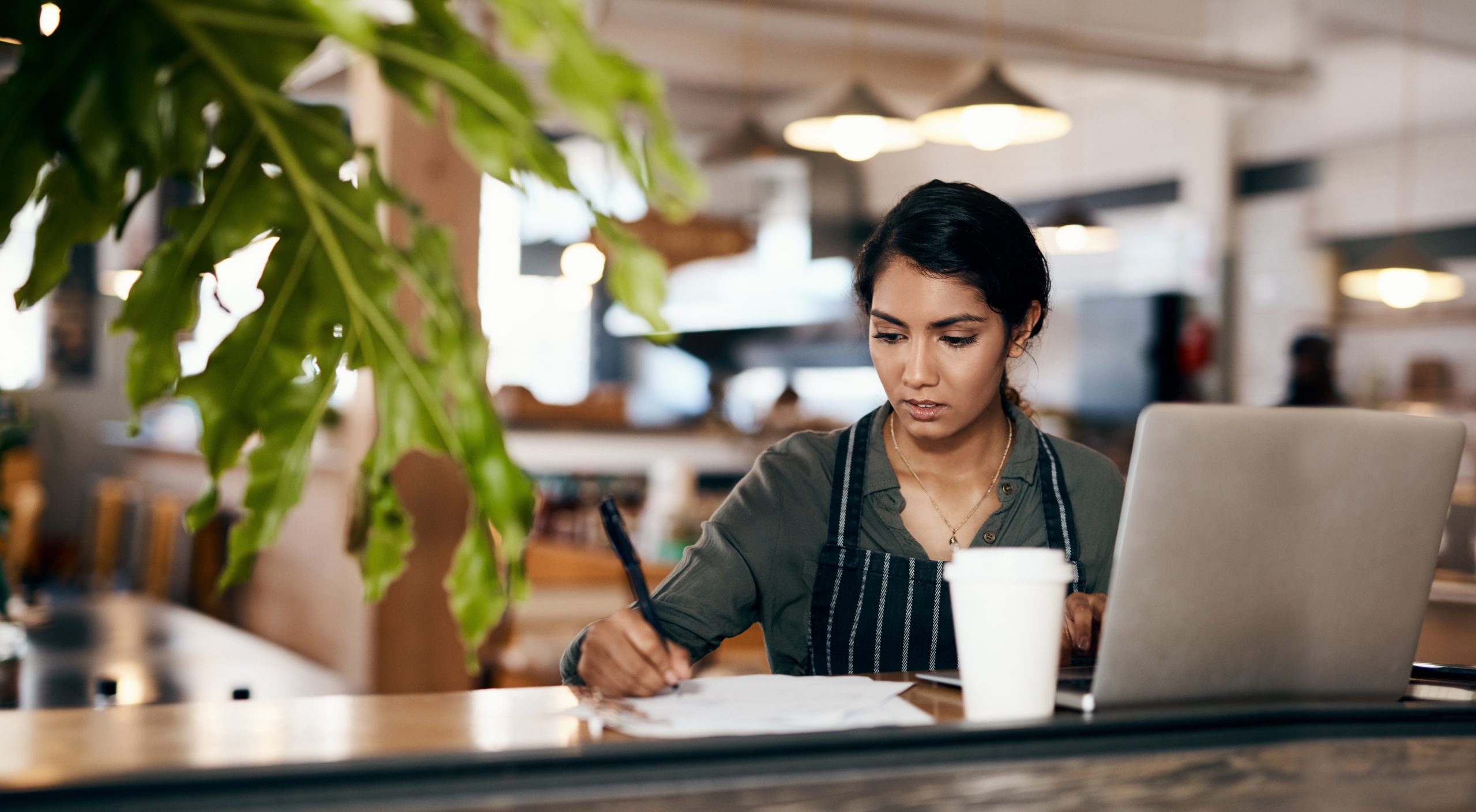 woman planning out her profit margins at a coffee shop